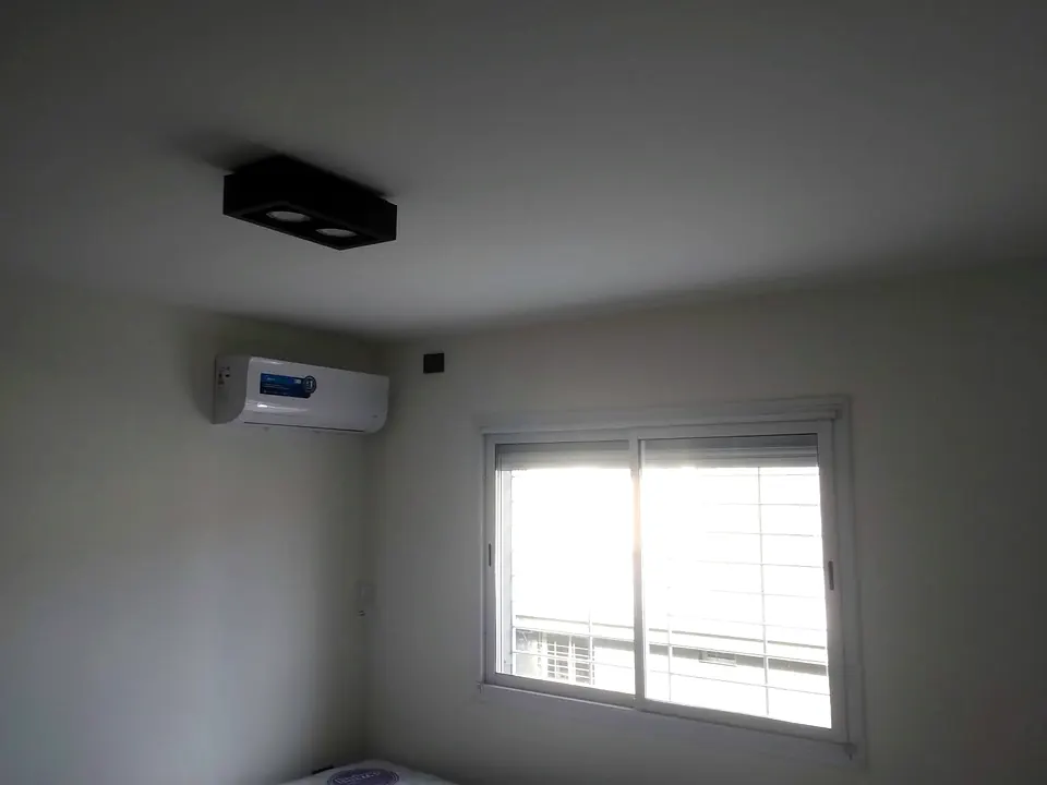Equipo de aire acondicionado split instalado en la pared de un dormitorio