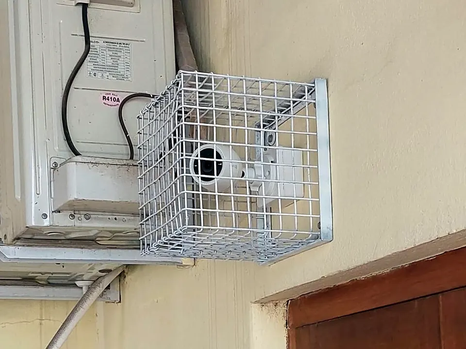 Cámara de seguridad dentro de una jaula metálica junto a un equipo de aire acondicionado